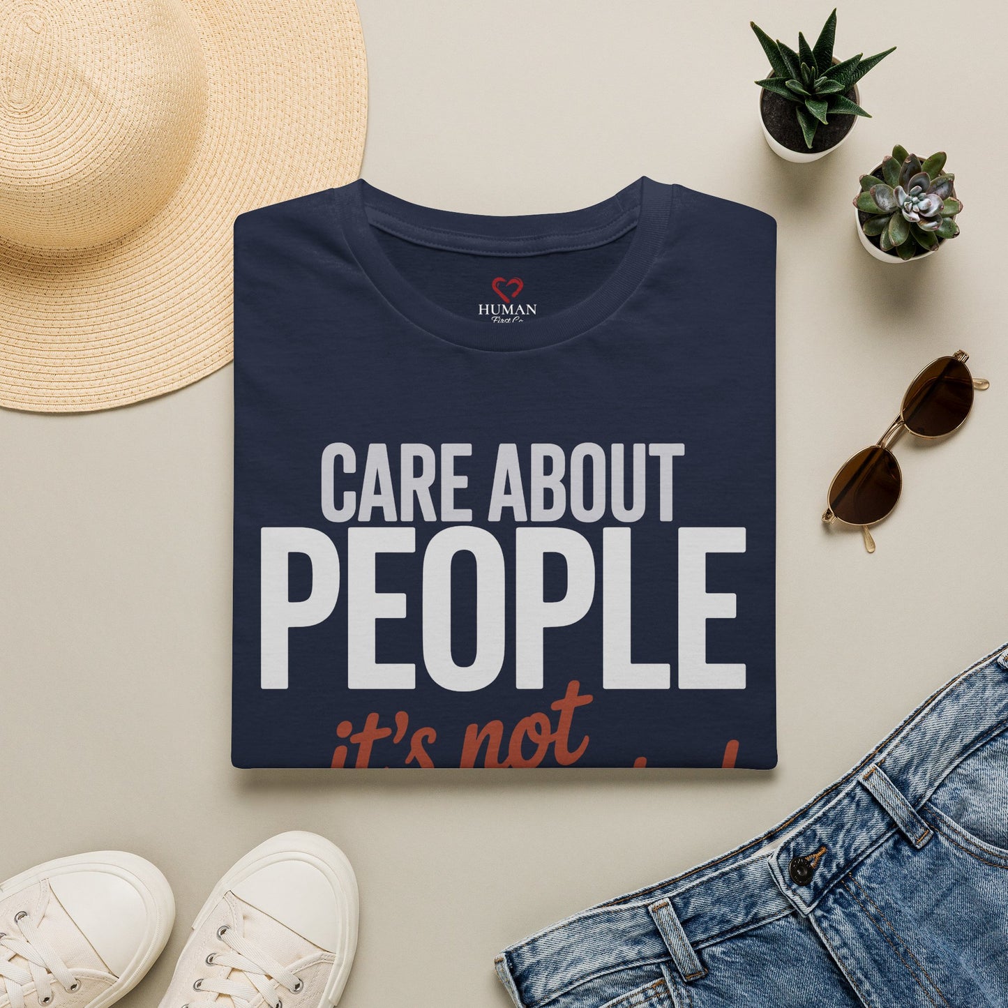 Folded humanitarian t-shirt featuring the Care About People design in a minimalist editorial presentation.