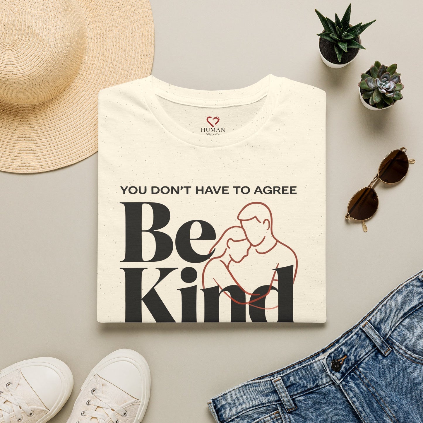 Folded humanitarian t-shirt featuring the Be Kind design in a minimalist editorial presentation.
