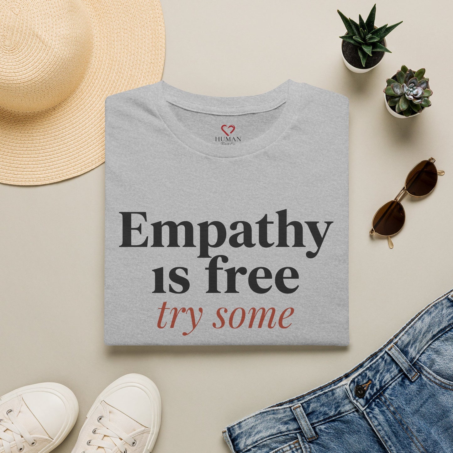 Folded humanitarian t-shirt featuring the Empathy Is Free design in a minimalist editorial presentation.